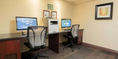 Business center with computers, printer and ergonomic chairs at Les Suites Hotel Ottawa.