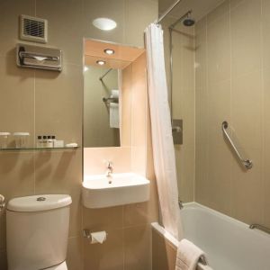 Guest bathroom with tub and free toiletries at Thistle London Heathrow Terminal 5.