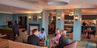 Dining area with comfortable seating and billiards at Thistle London Heathrow Terminal 5.