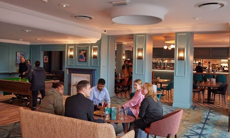 Dining area with comfortable seating and billiards at Thistle London Heathrow Terminal 5.