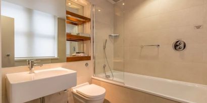 Guest bathroom with tub and free toiletries at Thistle Holborn, The Kingsley Hotel.