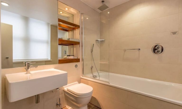 Guest bathroom with tub and free toiletries at Thistle Holborn, The Kingsley Hotel.