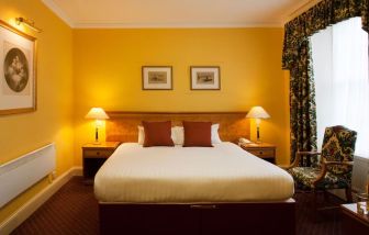 Single bed guest room in The Royal Highland Hotel, with bedside lamp and art on the wall.