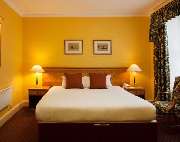 Single bed guest room in The Royal Highland Hotel, with bedside lamp and art on the wall.