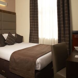 Queen bed and work desk at Mercure Hotel London Paddington.