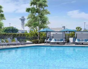 Refreshing outdoor pool with loungers and cabanas at Hyatt Regency Los Angeles International Airport.