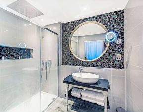 Guest bathroom with shower and free toiletries at Mercure Hotel London Hyde Park.