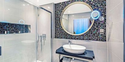 Guest bathroom with shower and free toiletries at Mercure Hotel London Hyde Park.