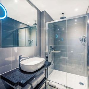 Guest bathroom with shower at Mercure Hotel London Hyde Park.