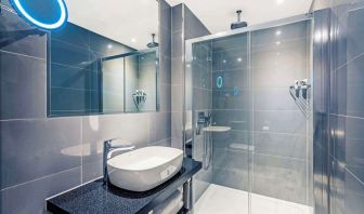 Guest bathroom with shower at Mercure Hotel London Hyde Park.