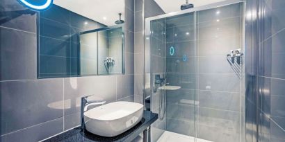 Guest bathroom with shower at Mercure Hotel London Hyde Park.