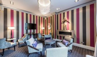 Lounge area with comfortable seating, TV screen and fireplace at Mercure Hotel London Hyde Park.