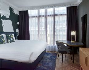 Bright and spacious day use room with king bed, TV screen and work desk at NYX Hotel London Holborn By Leonardo.