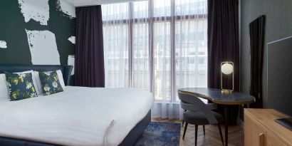 Bright and spacious day use room with king bed, TV screen and work desk at NYX Hotel London Holborn By Leonardo.