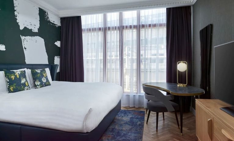 Bright and spacious day use room with king bed, TV screen and work desk at NYX Hotel London Holborn By Leonardo.