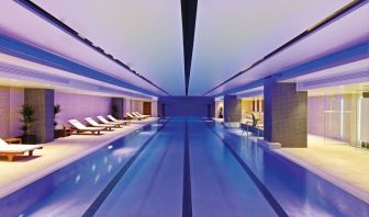 Relaxing indoor pool with lounge chairs at Leonardo Royal Hotel London Tower Bridge.