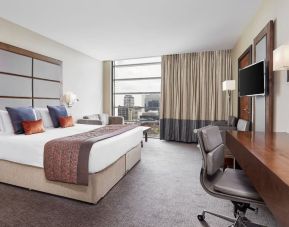 Day use room with TV, work desk and floor to ceiling windows with view of the city at Leonardo Royal Hotel London Tower Bridge.