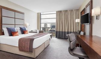 Day use room with TV, work desk and floor to ceiling windows with view of the city at Leonardo Royal Hotel London Tower Bridge.