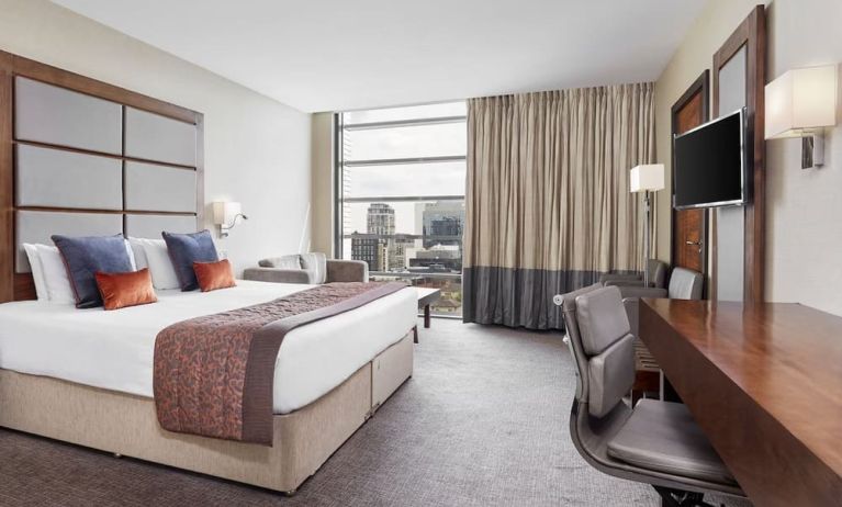 Day use room with TV, work desk and floor to ceiling windows with view of the city at Leonardo Royal Hotel London Tower Bridge.