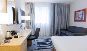 Day use room with work desk, TV screen and sofa at Novotel Manchester West.