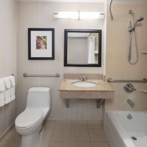 Guest bathroom with shower and tub at Hilton Garden Inn Queens/JFK Airport.