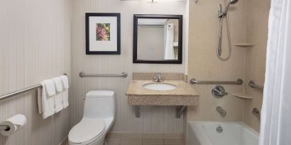 Guest bathroom with shower and tub at Hilton Garden Inn Queens/JFK Airport.