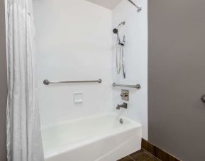 Guest bathroom with combined tub and shower at Hotel 1550 SFO.