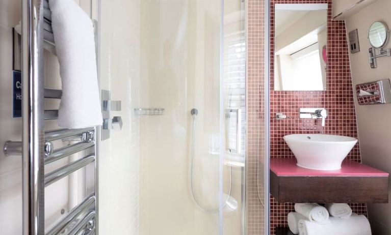 Private guest bathroom with shower and free toiletries at Indigo London-Paddington Hotel.