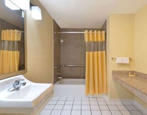 Guest bathroom with shower and tub at Days Inn By Wyndham San Antonio Northwest/Seaworld.