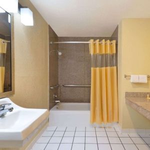 Guest bathroom with shower and tub at Days Inn By Wyndham San Antonio Northwest/Seaworld.