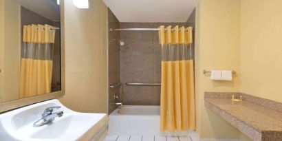 Guest bathroom with shower and tub at Days Inn By Wyndham San Antonio Northwest/Seaworld.