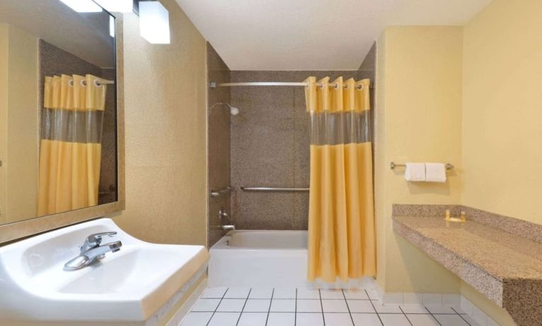 Guest bathroom with shower and tub at Days Inn By Wyndham San Antonio Northwest/Seaworld.