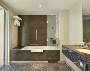 Guest bathroom with combined tub and shower at Hyatt Place London Heathrow Airport. 