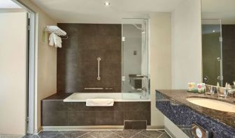 Guest bathroom with combined tub and shower at Hyatt Place London Heathrow Airport. 