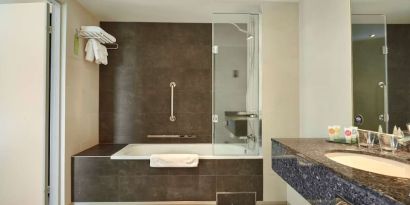 Guest bathroom with combined tub and shower at Hyatt Place London Heathrow Airport. 