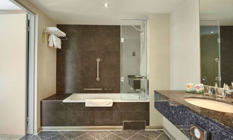 Guest bathroom with combined tub and shower at Hyatt Place London Heathrow Airport. 