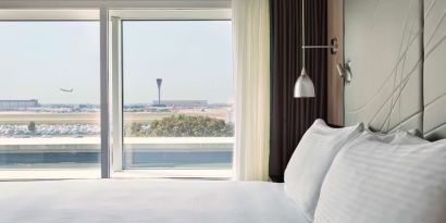 King bed with floor to ceiling window at Hyatt Place London Heathrow Airport.