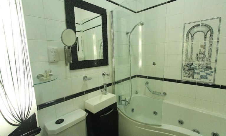 Private bathroom with tub and free toiletries at Opulence Central London Hotel.