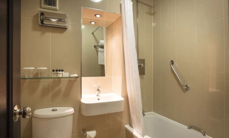 Guest bathroom with combined tub and shower at Thistle London Heathrow Terminal 5 Hotel.