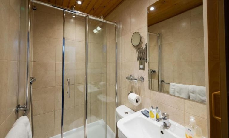 Private guest bathroom with shower and free toiletries at Adria Hotel.