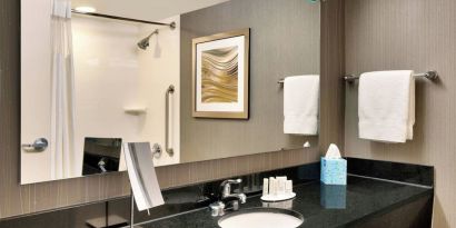 Guest bathroom with shower at Courtyard By Marriott Charlotte Airport/Billy Graham Parkway.