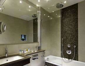 Guest bathroom with combined tub and shower at Blakemore Hyde Park Hotel.