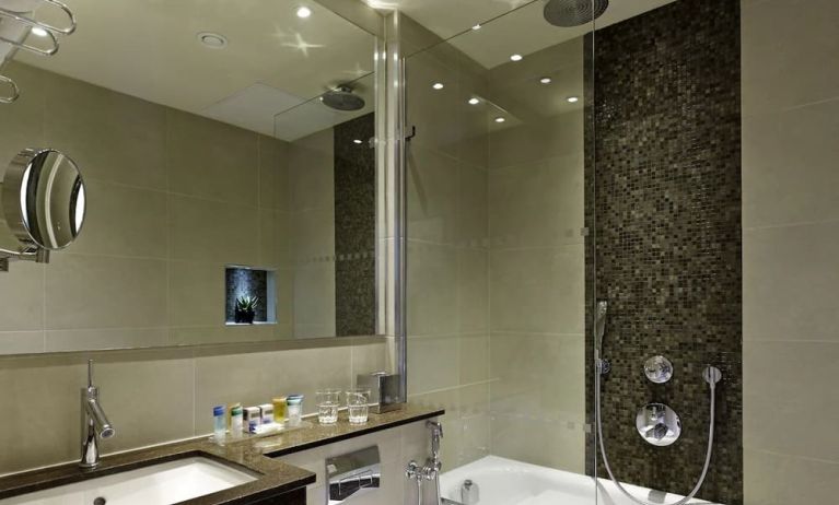 Guest bathroom with combined tub and shower at Blakemore Hyde Park Hotel.