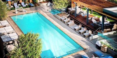 Refreshing outdoor pool surrounded by pool chairs at Hotel Nia, Autograph Collection.