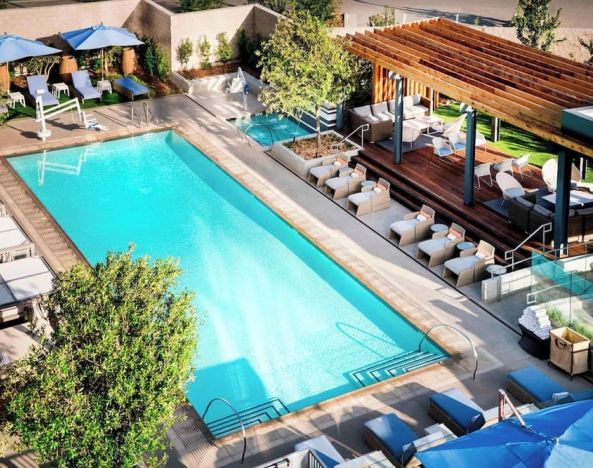 Refreshing outdoor pool surrounded by pool chairs at Hotel Nia, Autograph Collection.