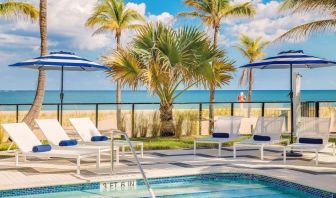 Refreshing outdoor pool surrounded by sun loungers with a view of the ocean at Plunge Beach Resort.
