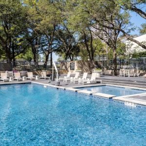 Refreshing outdoor pool surrounded by loungers at Hilton Dallas Lincoln Centre.