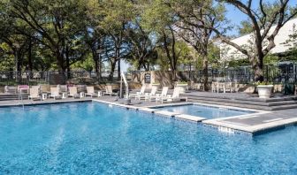 Refreshing outdoor pool surrounded by loungers at Hilton Dallas Lincoln Centre.