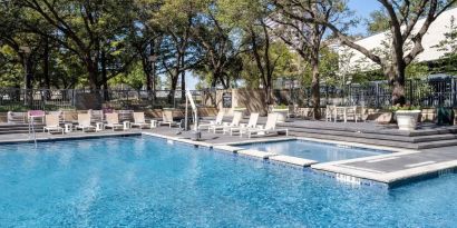 Refreshing outdoor pool surrounded by loungers at Hilton Dallas Lincoln Centre.