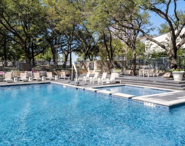 Refreshing outdoor pool surrounded by loungers at Hilton Dallas Lincoln Centre.